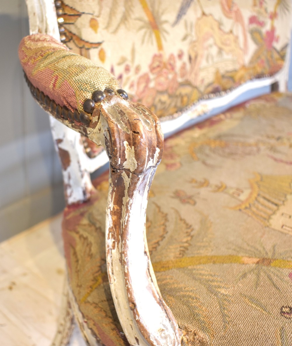 A French Louis XV style painted wooden settee with serpentine rails, cabriole legs, and woven tapestry upholstery featuring birds and palm trees. View VIII