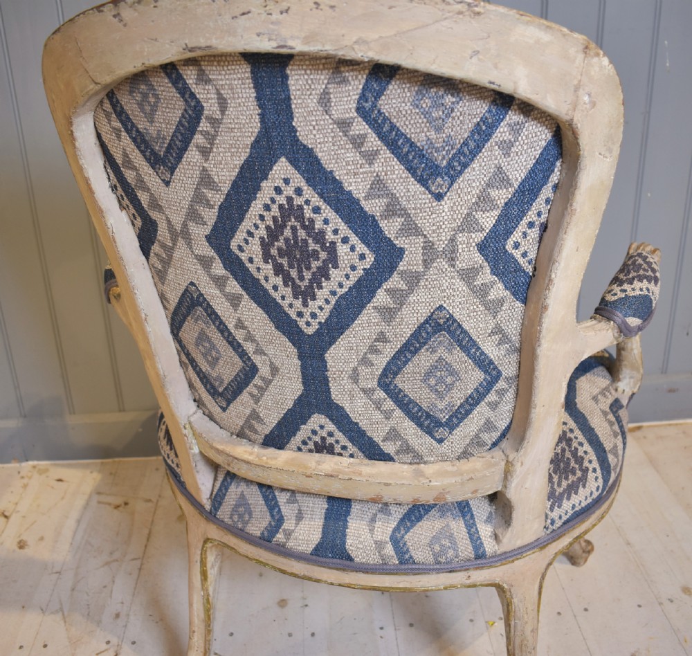 A French painted fauteuil armchair featuring cabriole legs, a carved cream frame with distressed finish, and blue geometric upholstery. View V