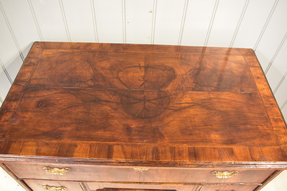 An early 18th-century George I walnut kneehole desk featuring brass handles, a central recessed cupboard, and bracket feet. View III