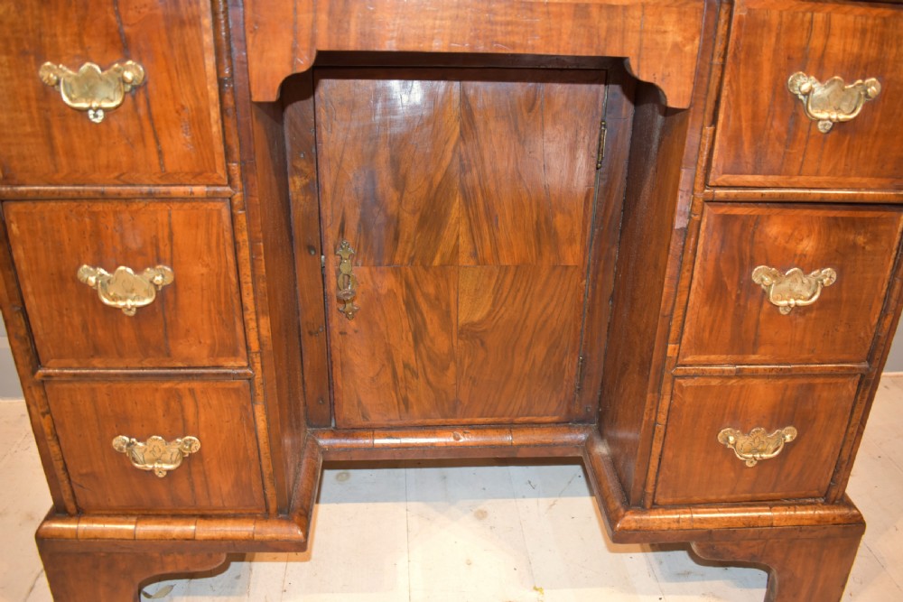 An early 18th-century George I walnut kneehole desk featuring brass handles, a central recessed cupboard, and bracket feet. View VII
