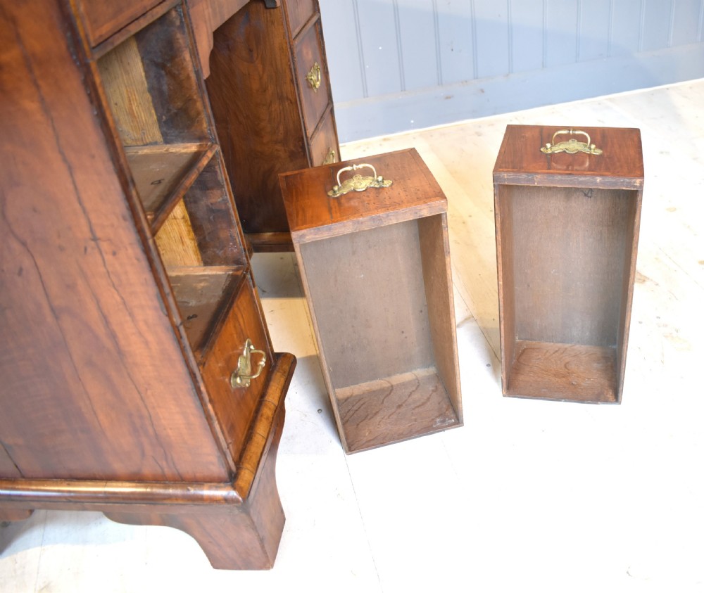 An early 18th-century George I walnut kneehole desk featuring brass handles, a central recessed cupboard, and bracket feet. View X