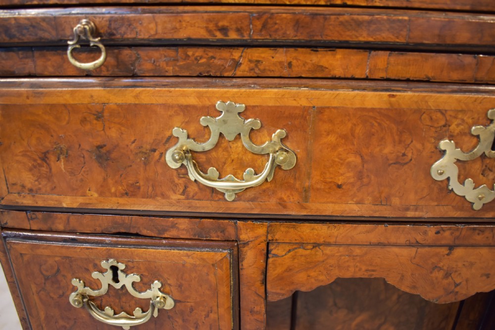 An antique Georgian style kneehole desk in burr walnut and burr oak veneers featuring brass handles, a central recessed cupboard, and drawers supported by bracket feet. View VI