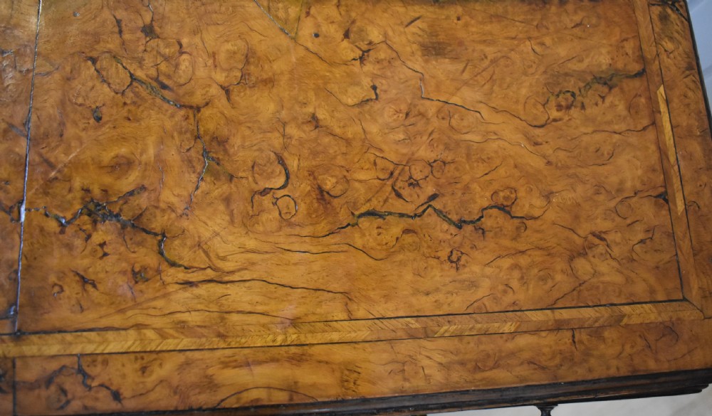 An antique Georgian style kneehole desk in burr walnut and burr oak veneers featuring brass handles, a central recessed cupboard, and drawers supported by bracket feet. View VII