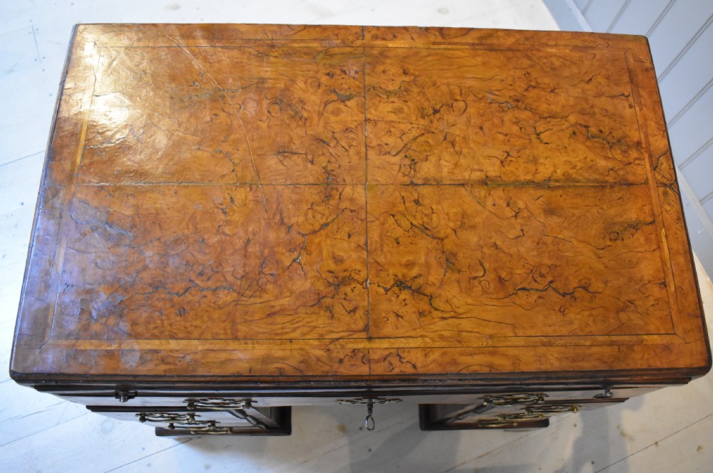 An antique Georgian style kneehole desk in burr walnut and burr oak veneers featuring brass handles, a central recessed cupboard, and drawers supported by bracket feet. View VIII