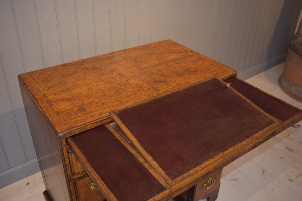 An antique Georgian style kneehole desk in burr walnut and burr oak veneers featuring brass handles, a central recessed cupboard, and drawers supported by bracket feet. View XII
