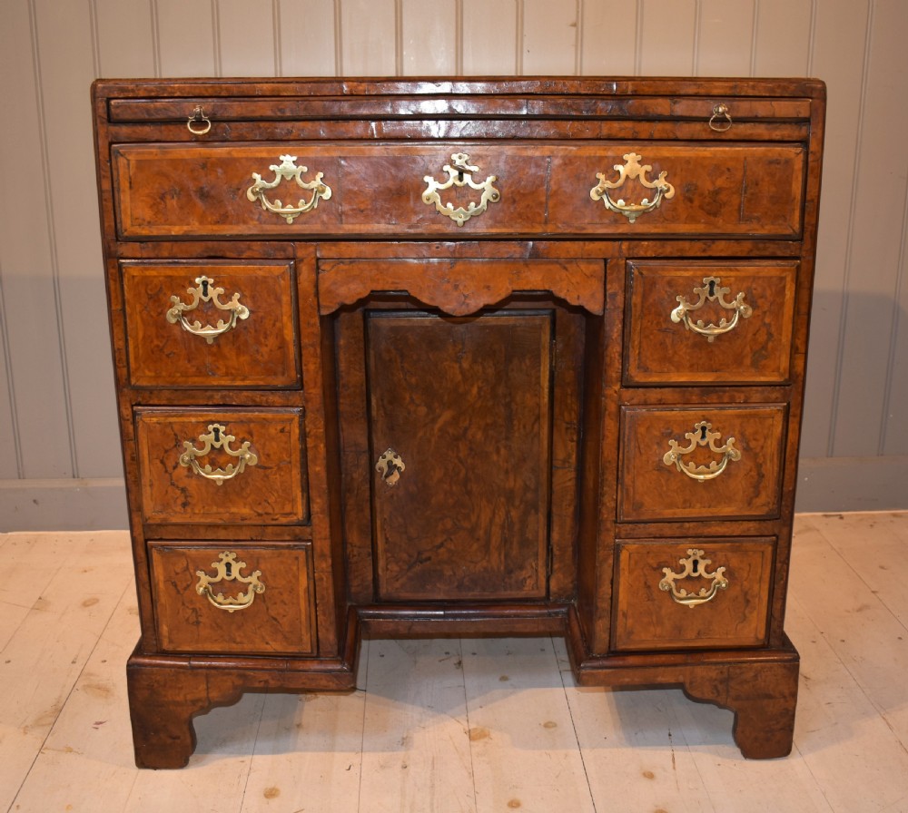 An antique Georgian style kneehole desk in burr walnut and burr oak veneers featuring brass handles, a central recessed cupboard, and drawers supported by bracket feet. View XIV