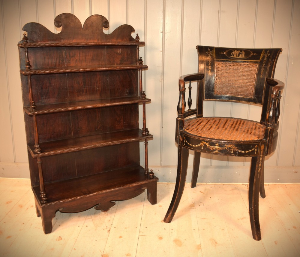 An antique dark mahogany open bookcase featuring four tiered shelves, turned spindle supports, beaded edging, and a carved scrolled crest. View II