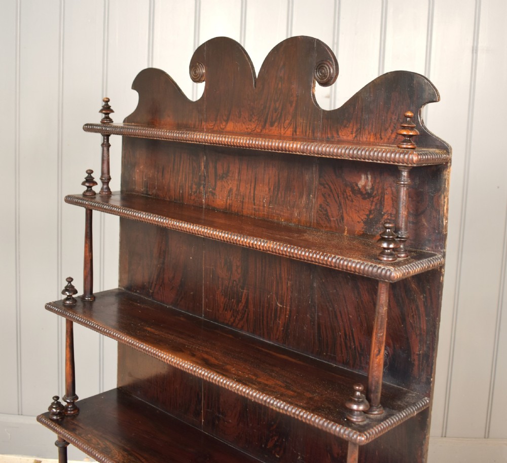 An antique dark mahogany open bookcase featuring four tiered shelves, turned spindle supports, beaded edging, and a carved scrolled crest. View VI