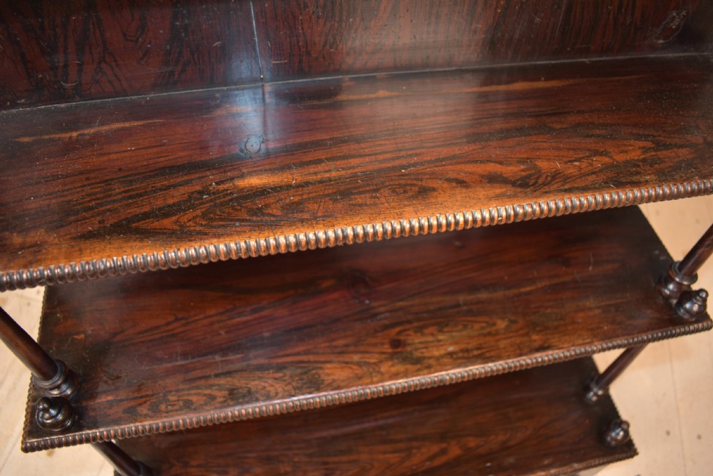 An antique dark mahogany open bookcase featuring four tiered shelves, turned spindle supports, beaded edging, and a carved scrolled crest. View VII