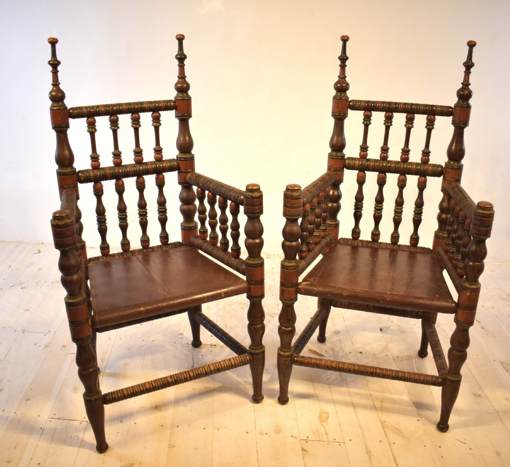 A pair of antique Swedish turned wood armchairs featuring bobbin spindles, tall finials, and dark red and brown paint details. View II