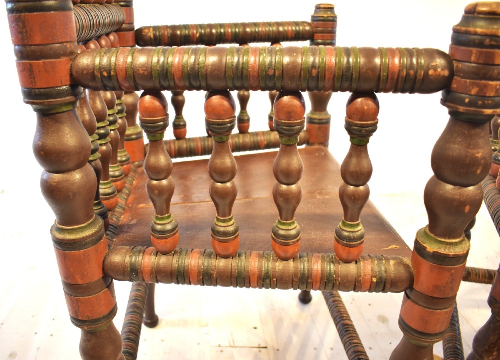 A pair of antique Swedish turned wood armchairs featuring bobbin spindles, tall finials, and dark red and brown paint details. View III