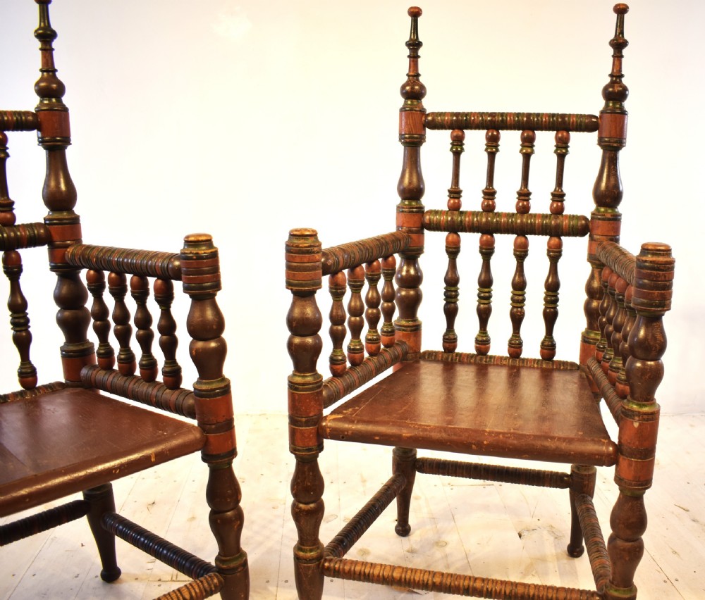 A pair of antique Swedish turned wood armchairs featuring bobbin spindles, tall finials, and dark red and brown paint details. View V