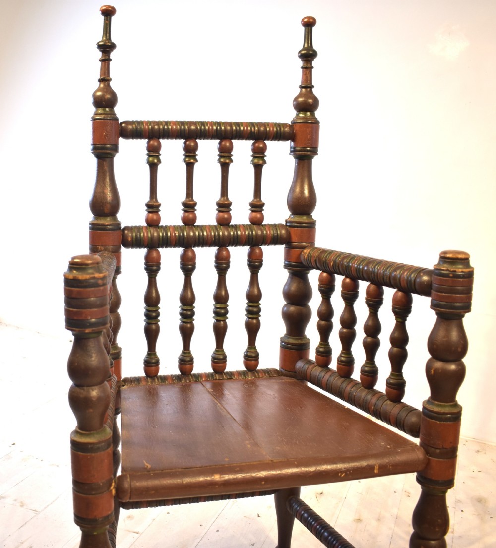 A pair of antique Swedish turned wood armchairs featuring bobbin spindles, tall finials, and dark red and brown paint details. View VI