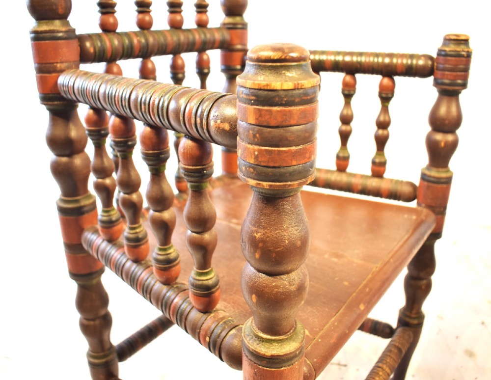 A pair of antique Swedish turned wood armchairs featuring bobbin spindles, tall finials, and dark red and brown paint details. View VIII