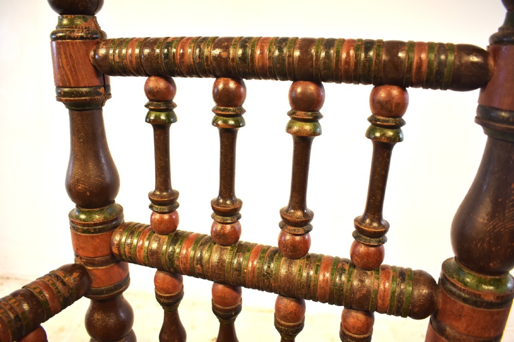 A pair of antique Swedish turned wood armchairs featuring bobbin spindles, tall finials, and dark red and brown paint details. View IX
