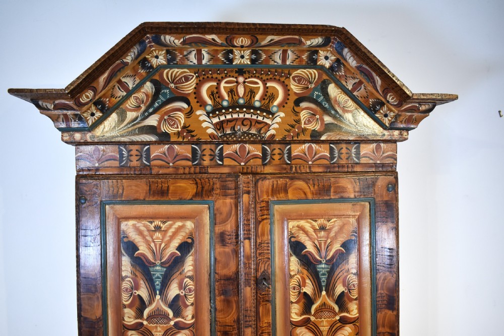 A two-tier Swedish painted pine corner cupboard decorated with hand-painted floral motifs and an arched pediment. View II