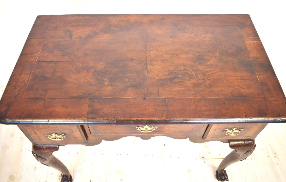 An antique Queen Anne walnut lowboy table featuring three drawers, brass handles, a shaped apron, and carved cabriole legs ending in ball and claw feet. View III
