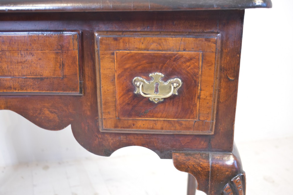An antique Queen Anne walnut lowboy table featuring three drawers, brass handles, a shaped apron, and carved cabriole legs ending in ball and claw feet. View XI