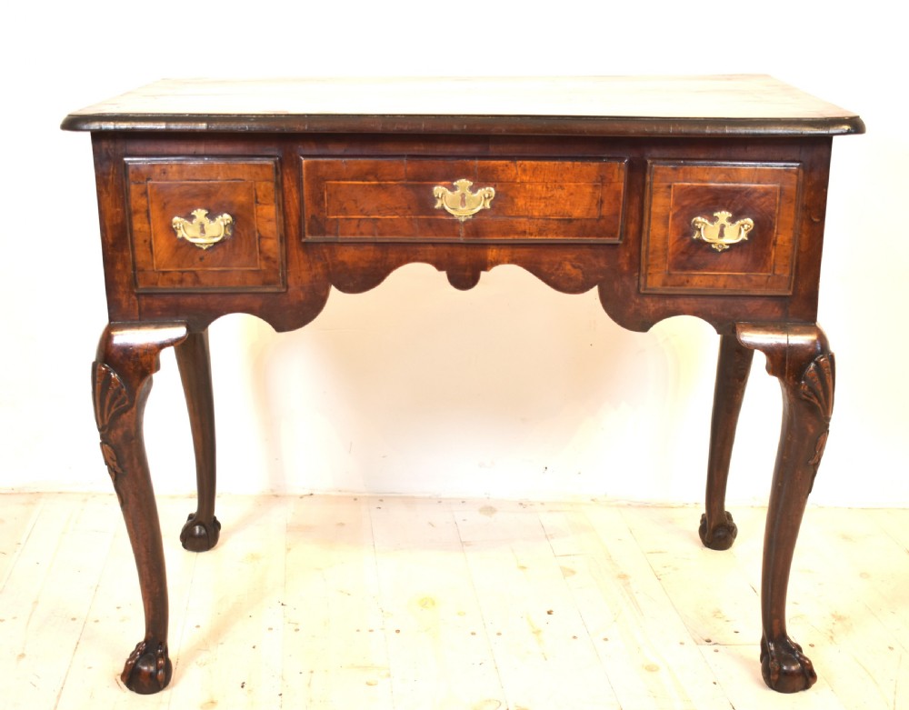 An antique Queen Anne walnut lowboy table featuring three drawers, brass handles, a shaped apron, and carved cabriole legs ending in ball and claw feet. View XII