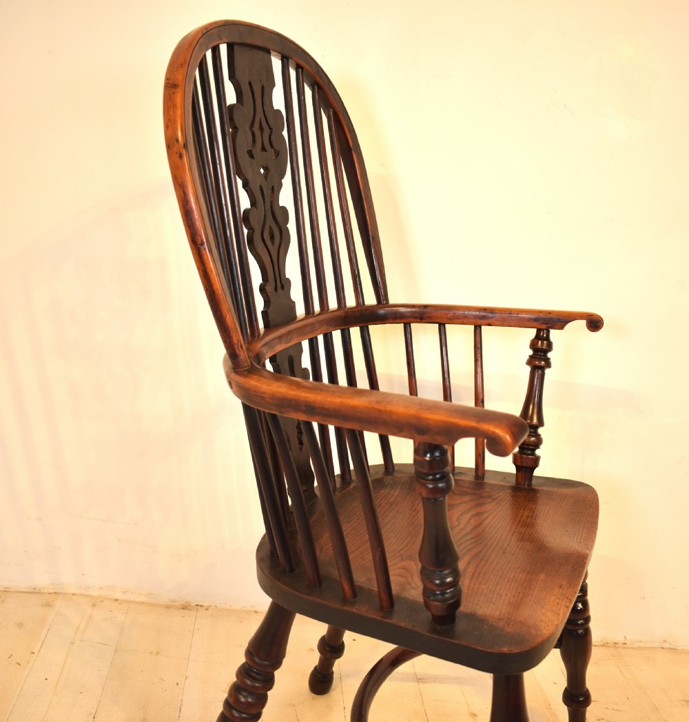 An antique yew wood Windsor armchair featuring a high hoop back with a decorative pierced splat, turned spindles, a shaped saddle seat, and turned legs joined by a curved stretcher. View II