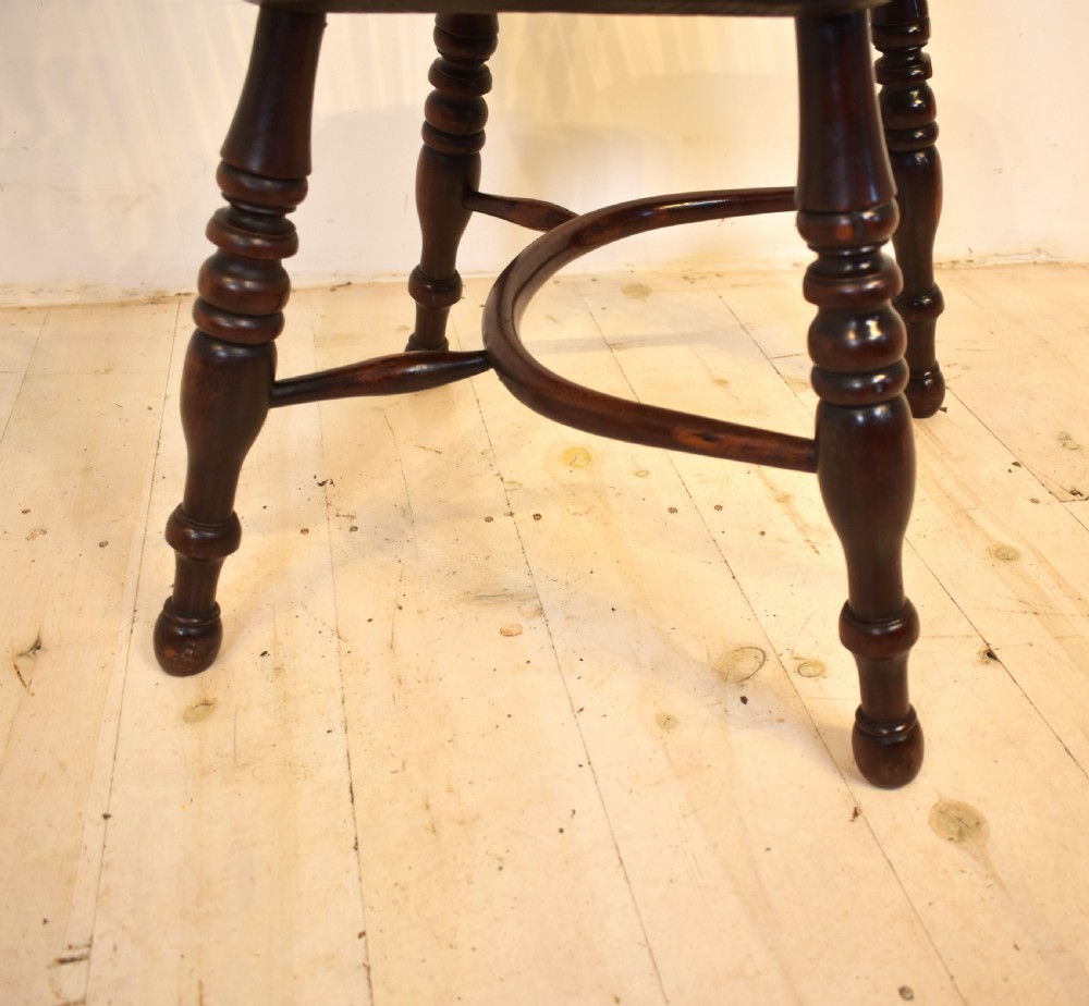 An antique yew wood Windsor armchair featuring a high hoop back with a decorative pierced splat, turned spindles, a shaped saddle seat, and turned legs joined by a curved stretcher. View III