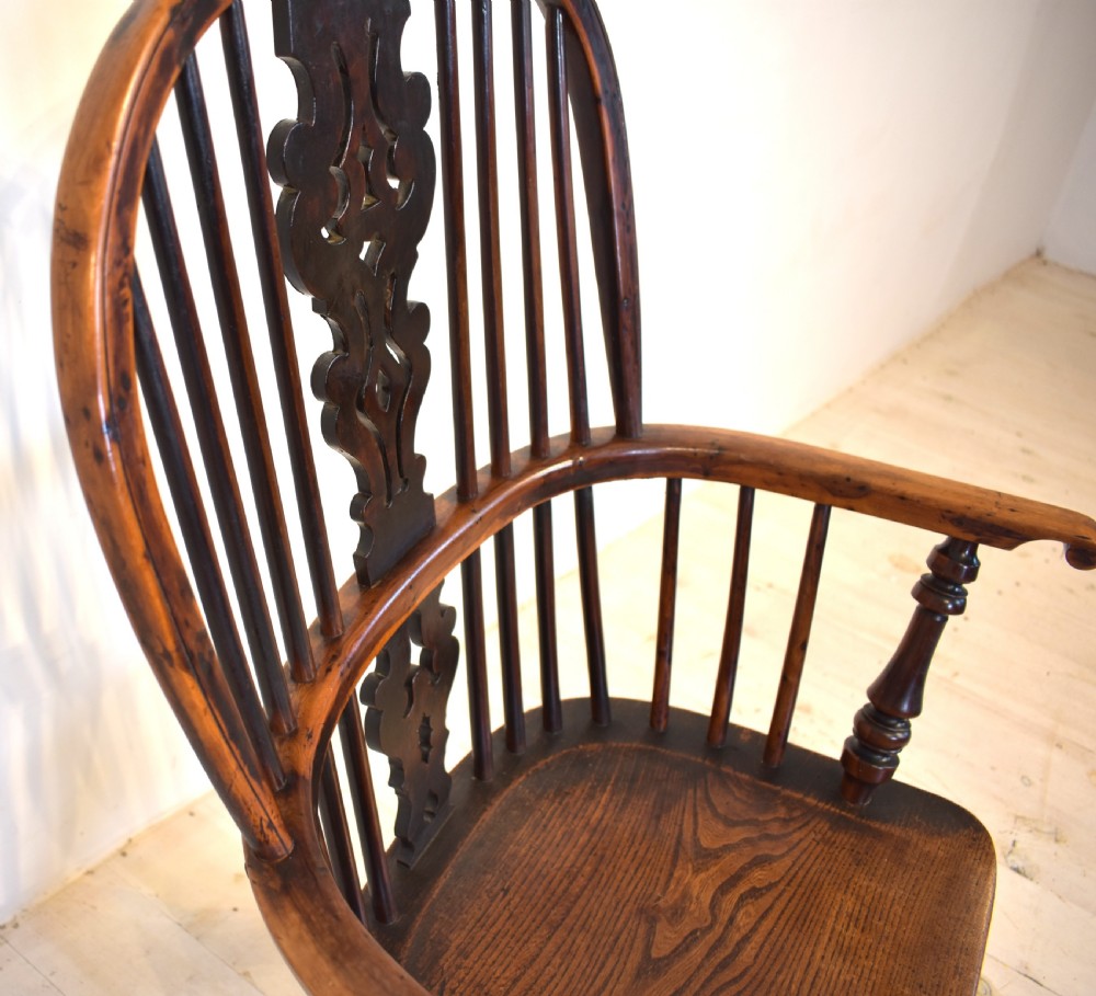 An antique yew wood Windsor armchair featuring a high hoop back with a decorative pierced splat, turned spindles, a shaped saddle seat, and turned legs joined by a curved stretcher. View IV
