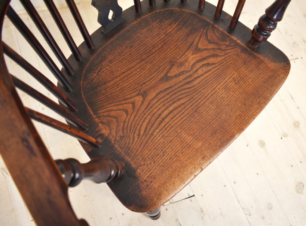 An antique yew wood Windsor armchair featuring a high hoop back with a decorative pierced splat, turned spindles, a shaped saddle seat, and turned legs joined by a curved stretcher. View V