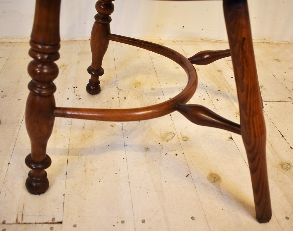 An antique wooden stick back Windsor armchair featuring a curved hoop backrest, spindle supports, a saddle seat, turned front legs, and a rich warm brown patina. View VI