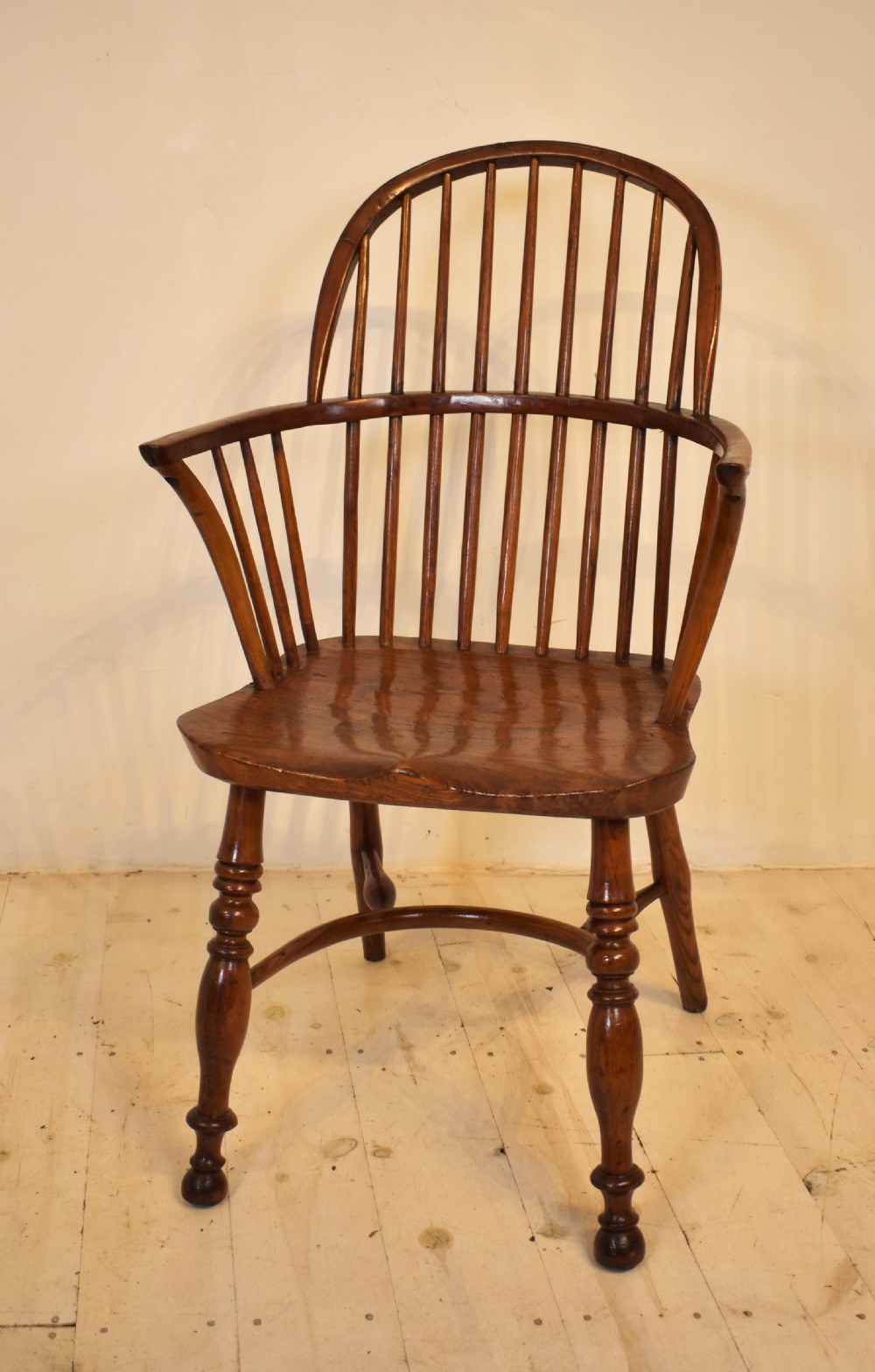 An antique wooden stick back Windsor armchair featuring a curved hoop backrest, spindle supports, a saddle seat, turned front legs, and a rich warm brown patina. View VII
