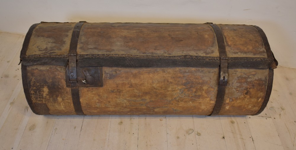 An antique cylindrical hide-covered coffer bound with dark leather trim and heavy iron bands with side handles. View II