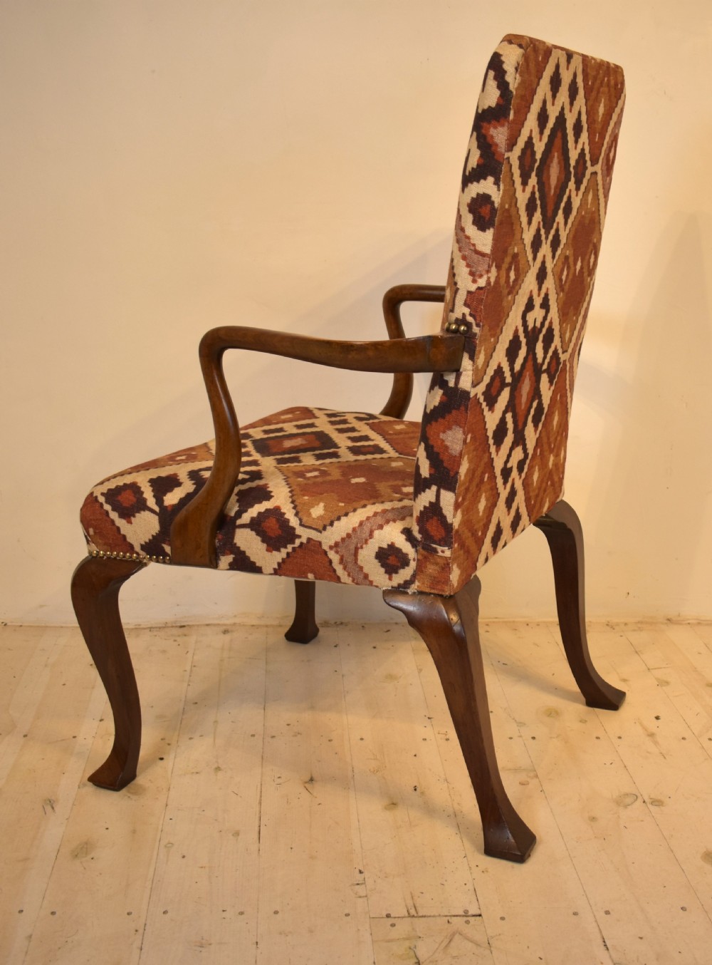 A walnut open armchair with cabriole front legs, shaped wooden arms, brass studding, and geometric terracotta tapestry upholstery. View IV