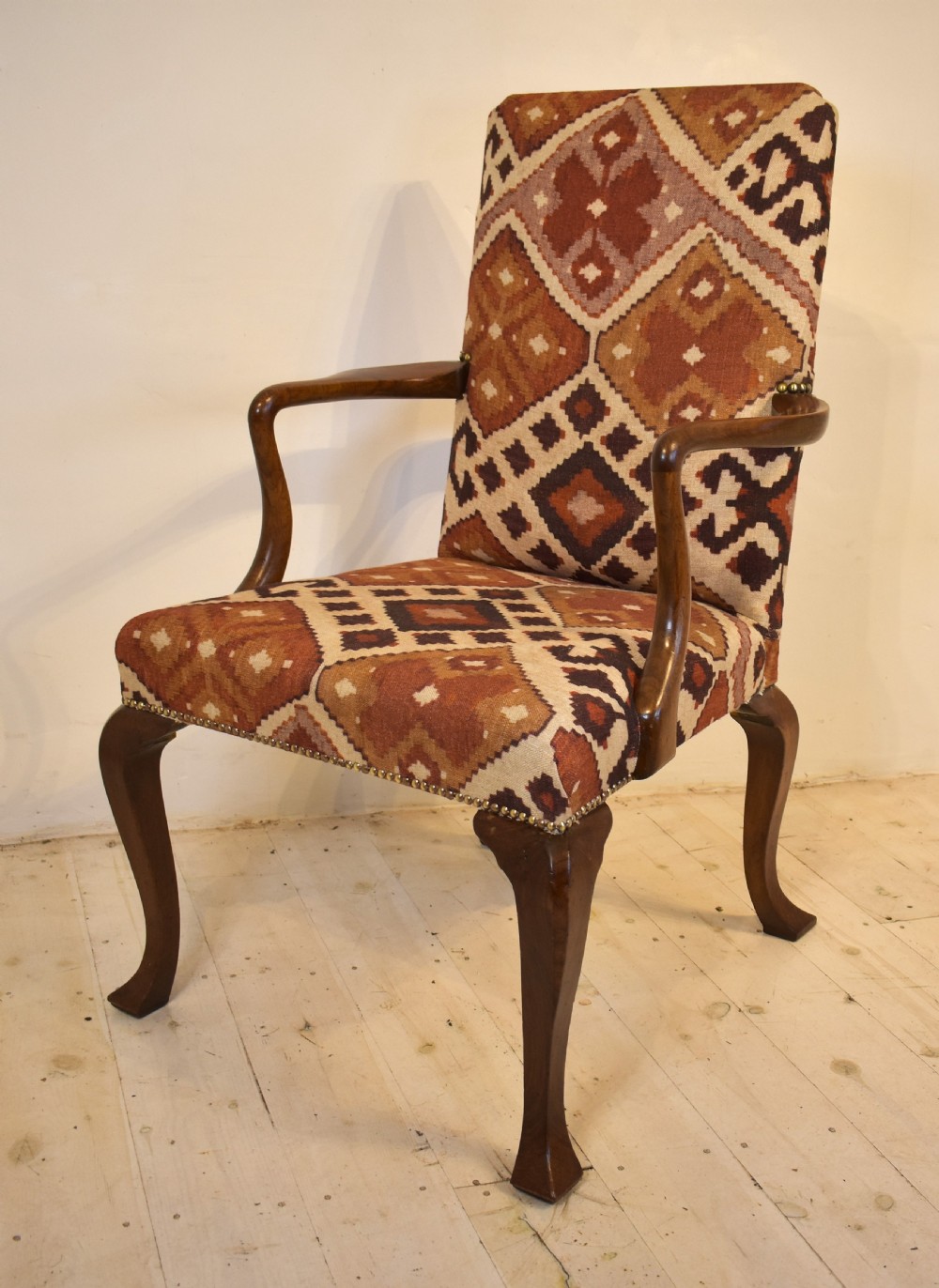 A walnut open armchair with cabriole front legs, shaped wooden arms, brass studding, and geometric terracotta tapestry upholstery. View V