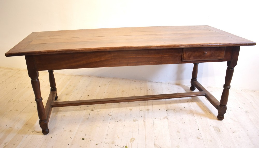 A rustic wooden farmhouse dining table featuring a plank top, a single side drawer, turned legs, and an H-stretcher base. View II