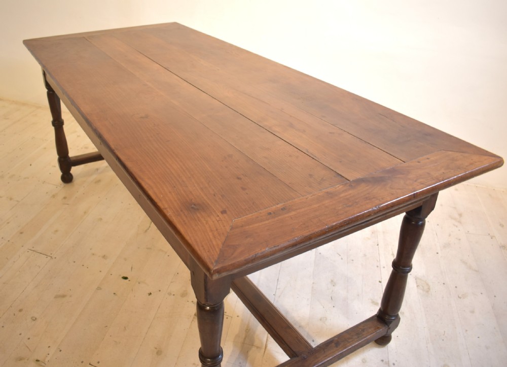 A rustic wooden farmhouse dining table featuring a plank top, a single side drawer, turned legs, and an H-stretcher base. View IX