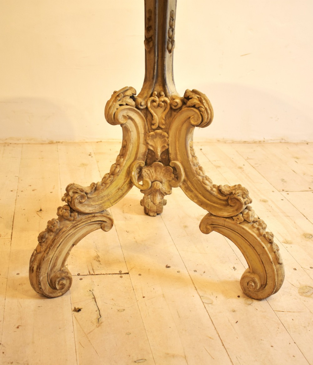 A circular grey marble top table supported by a carved cream painted pedestal base with tripod scroll feet. View III