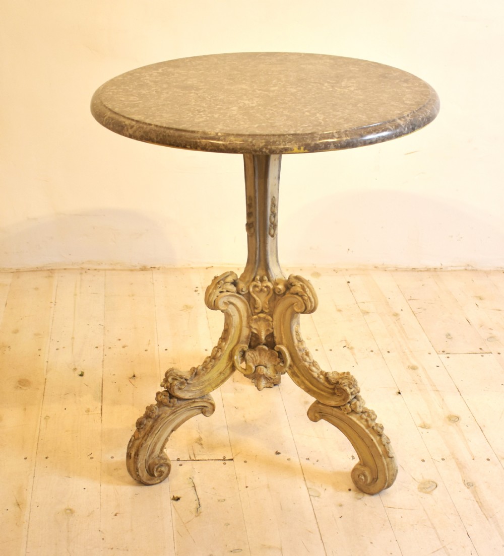 A circular grey marble top table supported by a carved cream painted pedestal base with tripod scroll feet. View VI