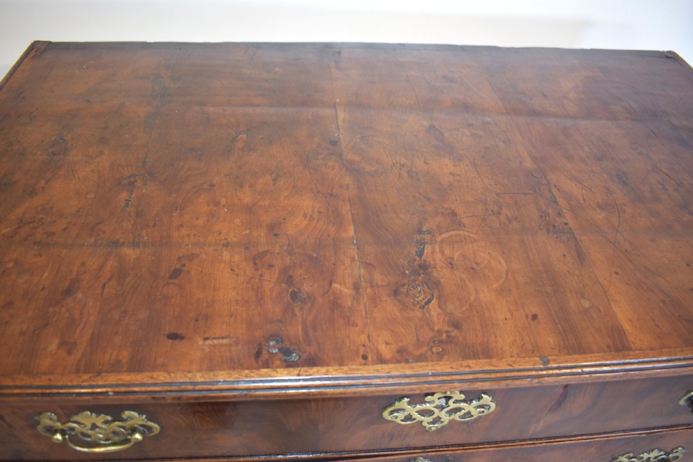 A Georgian yew wood chest of drawers featuring four graduated long drawers with ornate brass drop handles and bracket feet. View X
