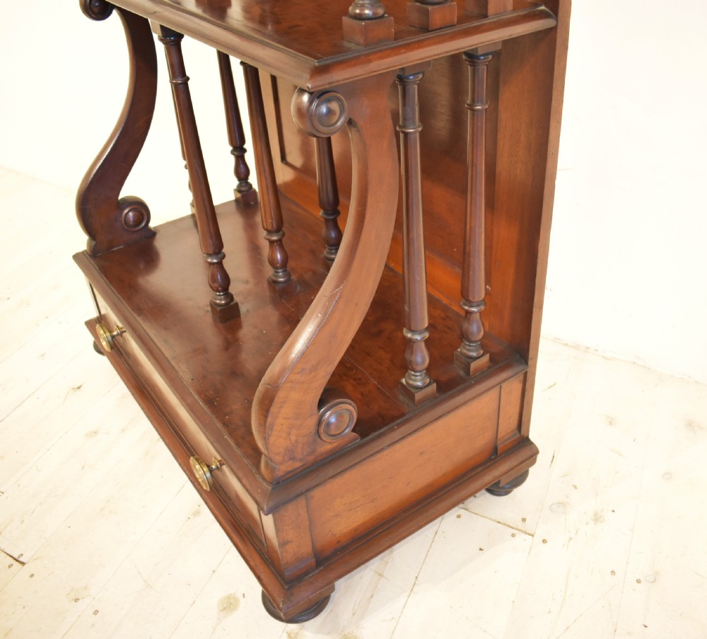 A dark mahogany waterfall bookcase featuring four graduated open shelves supported by turned spindles, curved side supports, and a base drawer with two brass knobs. View VI