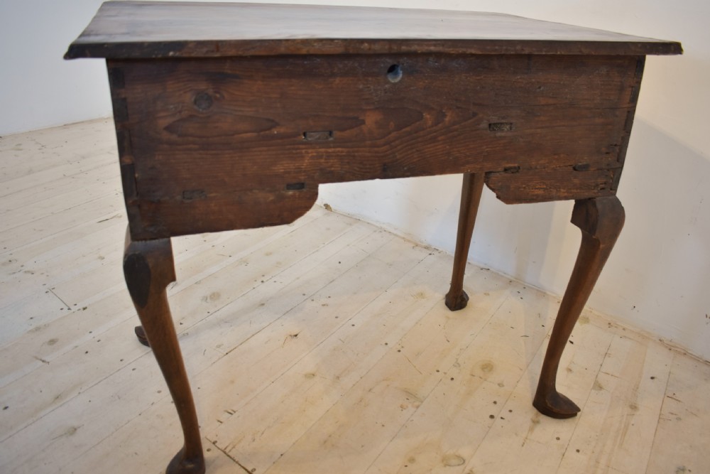 An antique Queen Anne style walnut lowboy featuring three crossbanded drawers with brass drop handles, a scalloped apron, and slender cabriole legs. View VII