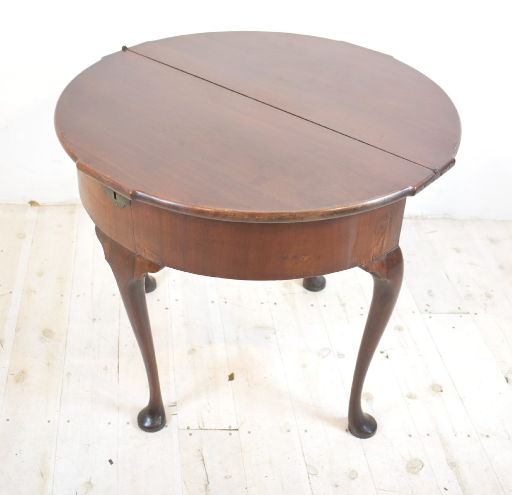 An early 18th-century mahogany demi-lune fold-over tea table featuring slender cabriole legs with pad feet and a central brass keyhole escutcheon. View III