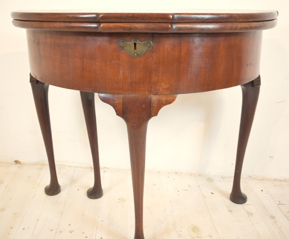 An early 18th-century mahogany demi-lune fold-over tea table featuring slender cabriole legs with pad feet and a central brass keyhole escutcheon. View VI