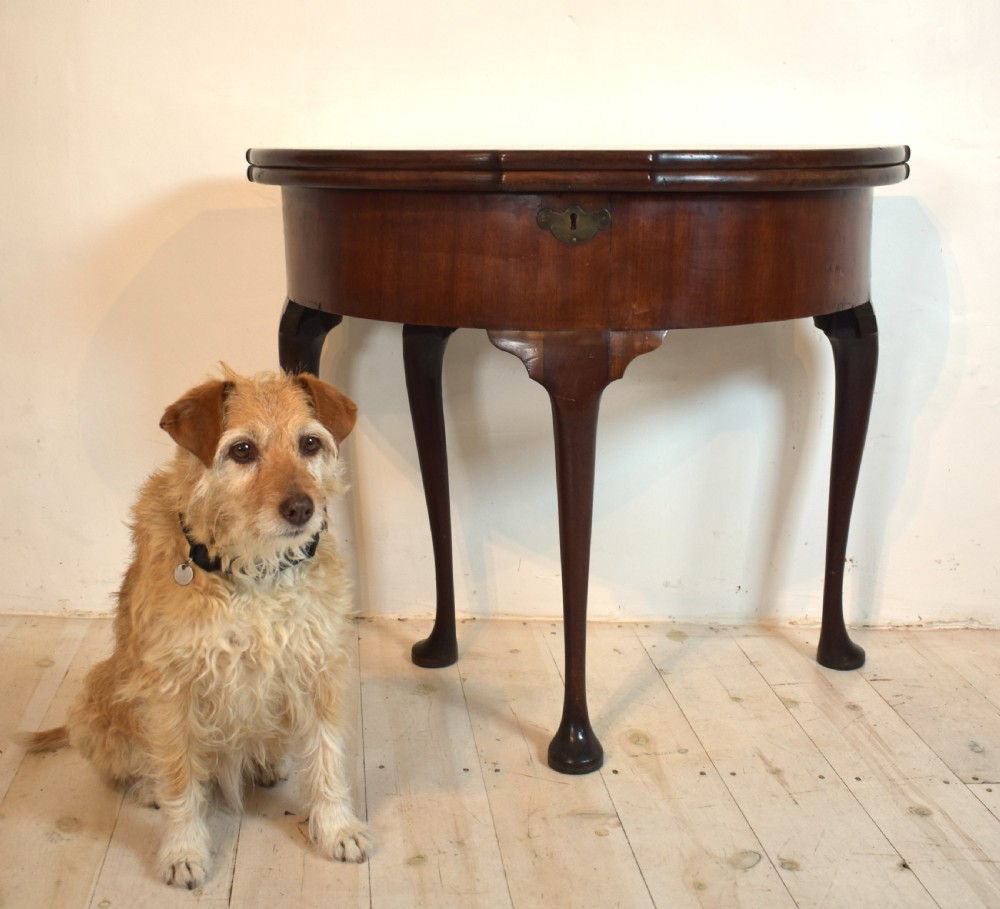 An early 18th-century mahogany demi-lune fold-over tea table featuring slender cabriole legs with pad feet and a central brass keyhole escutcheon. View VIII