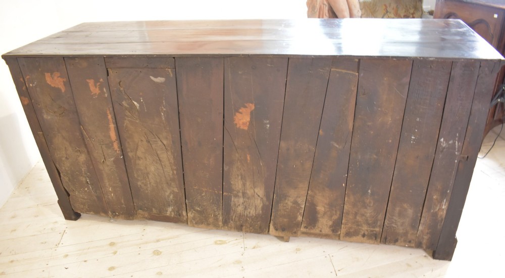An eighteenth-century dark oak Lancashire dresser base featuring a central fielded panel cupboard door flanked by multiple drawers with brass batwing drop handles. View VIII