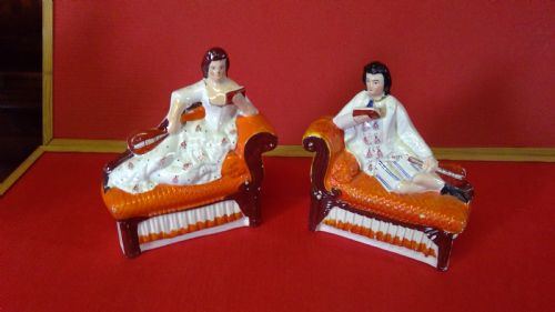 pair of rare antique Staffordshire pottery flat back figures or book ends depicting a boy and girl reading sitting on a regency sofa