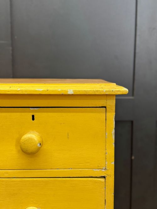 fig 2. An antique yellow painted pine chest of drawers featuring two short drawers over two long drawers with matching turned wooden knobs and a solid plinth base.