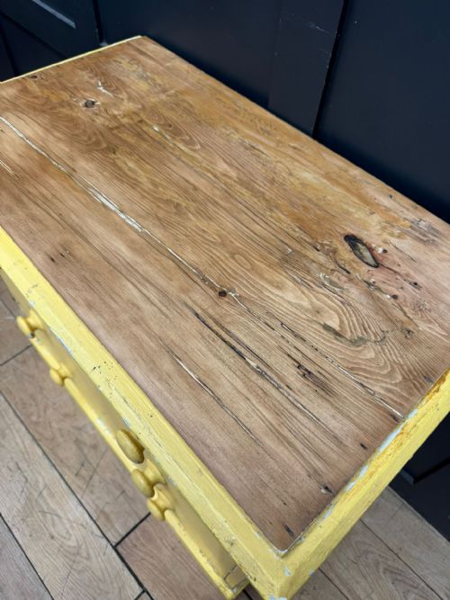 fig 4. An antique yellow painted pine chest of drawers featuring two short drawers over two long drawers with matching turned wooden knobs and a solid plinth base.