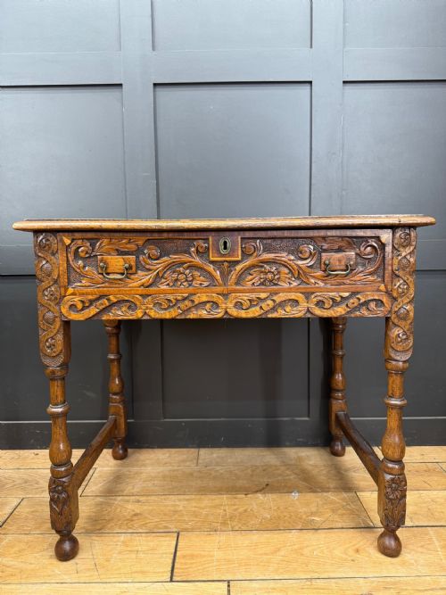 fig 1. An antique carved oak side table featuring turned legs, a single carved drawer with brass handles, and lower stretchers.