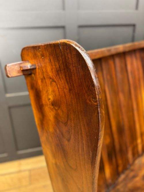 fig 1. A curved antique elm wooden settle pew featuring a slatted high back, shaped side wings, and visible pegged joinery.