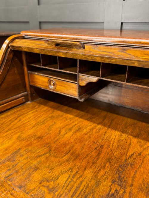 fig 1. An Edwardian oak roll top pedestal desk featuring a flexible wooden tambour cover and twin drawer pedestals with carved handles.