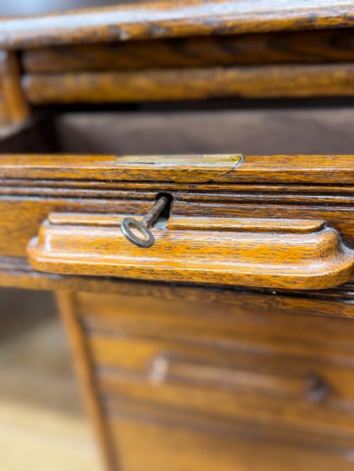 fig 3. An Edwardian oak roll top pedestal desk featuring a flexible wooden tambour cover and twin drawer pedestals with carved handles.